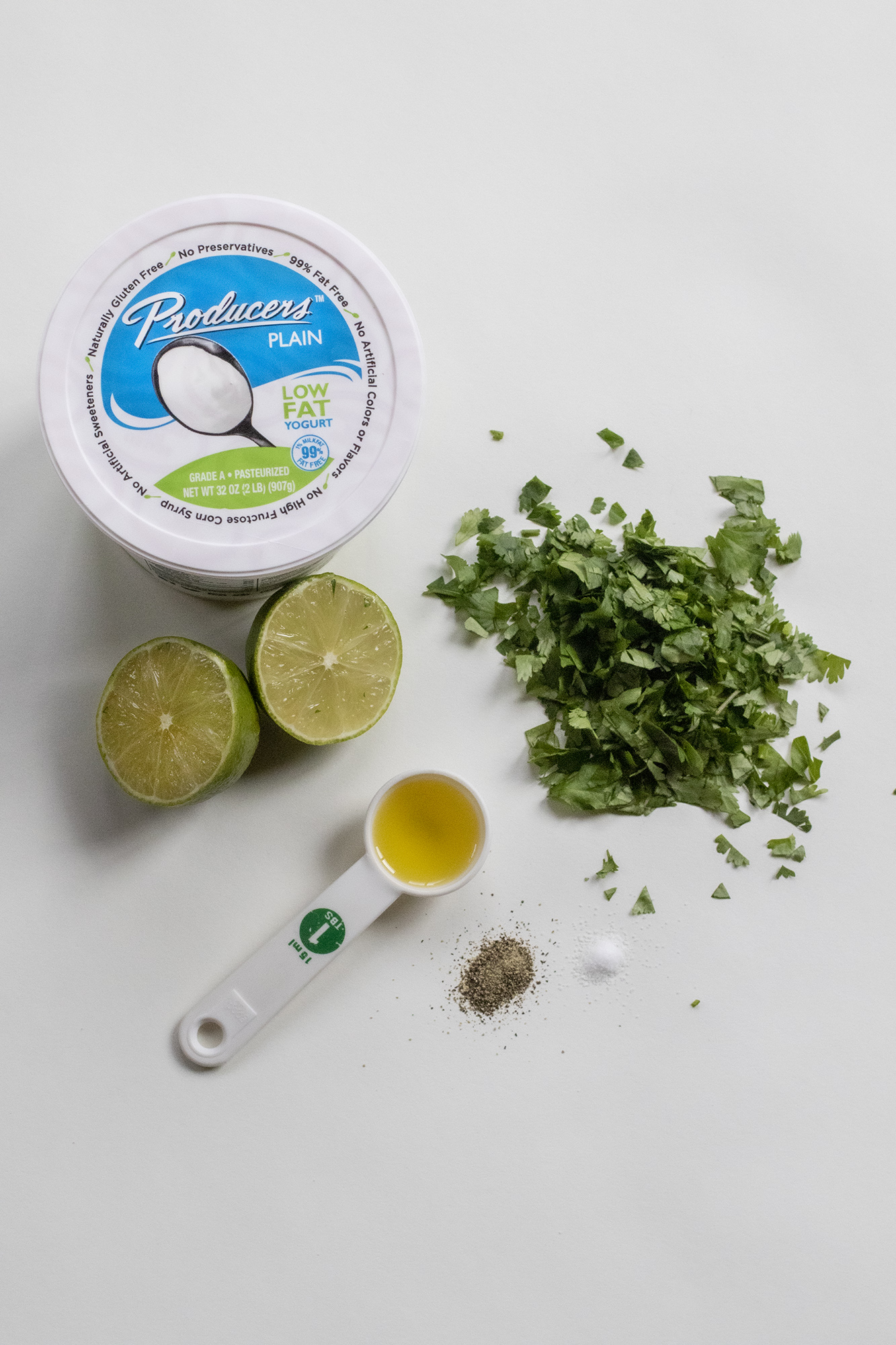 Producers plain yogurt surrounded by a lime cut in half, I tbsp. of olive oil, salt & pepper, and diced cilantro.