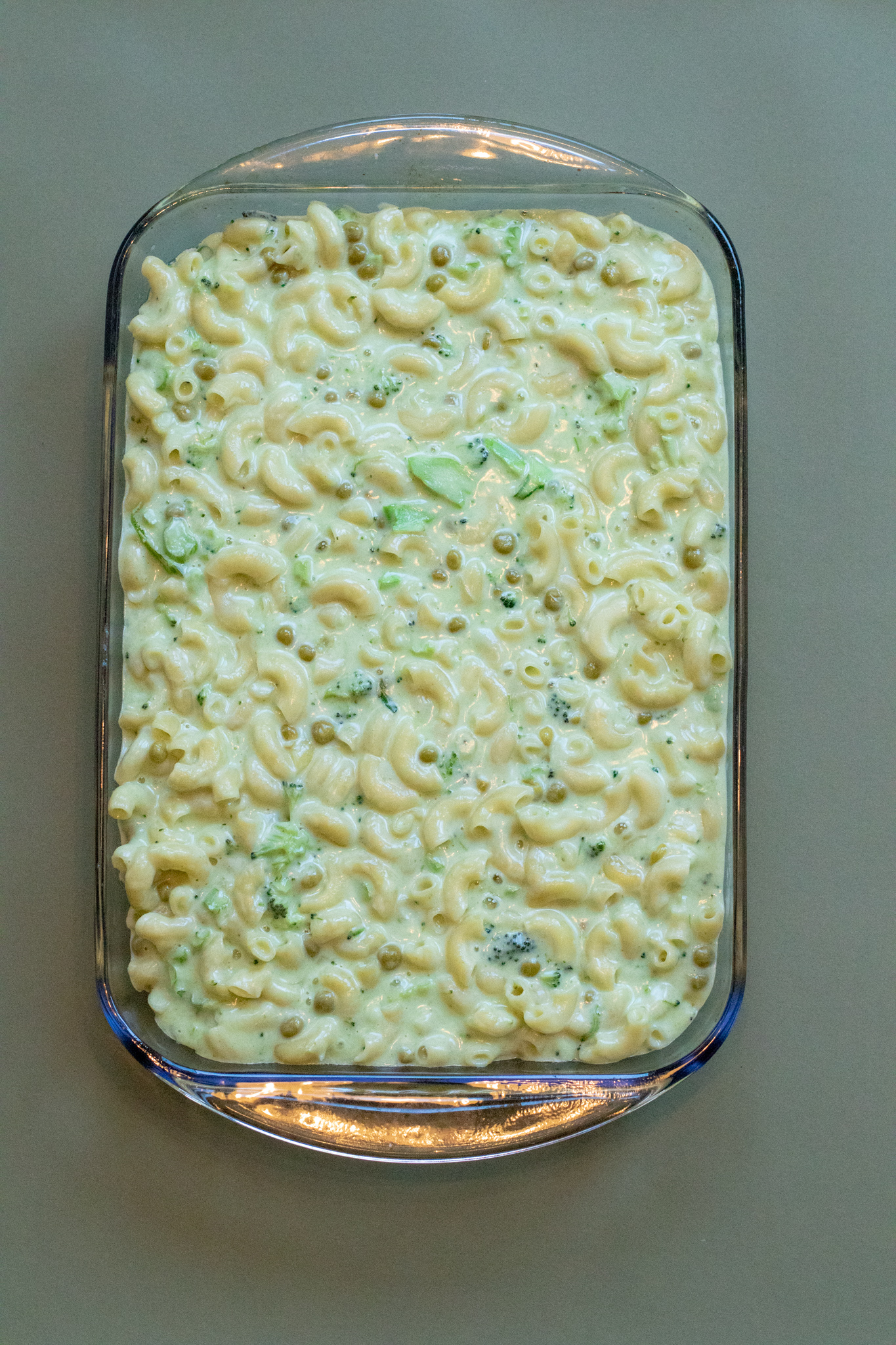 veggie macaroni and cheese in a baking dish with a green background.